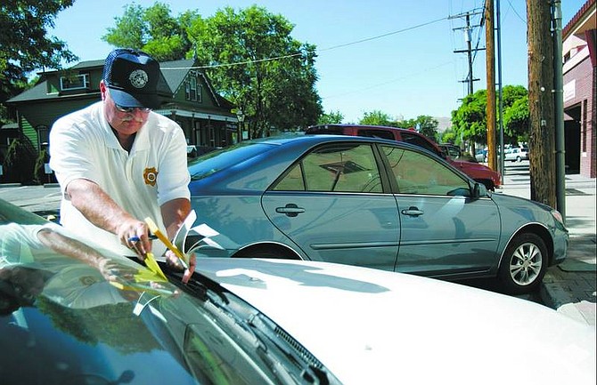 photos by Chad Lundquist/Nevada Appeal Compliance Officer Allan A. Biddle places a parking ticket on the windshield of a car during his rounds Monday afternoon.