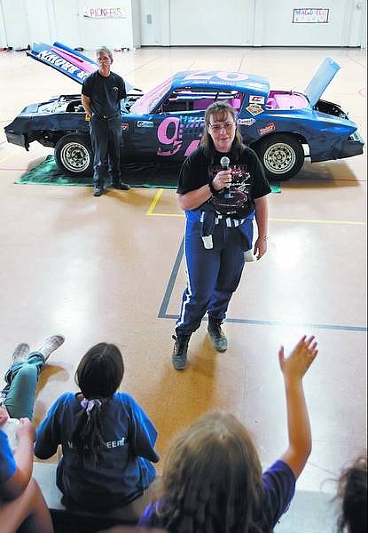 Chad Lundquist/Nevada Appeal Race car driver Janet Wainscott answers questions for kids from the Carson City Community Center day camp Monday. Wainscott, and her sponsor Roger Brown, rear, from Roger Brown Automotive, brought her 1979 Z28 Camaro to the community center for the day as part of a show and tell type event for the kids. Wainscott, took her first checkered flag last week in the hobby stock class at Reno/Fernley Raceway.