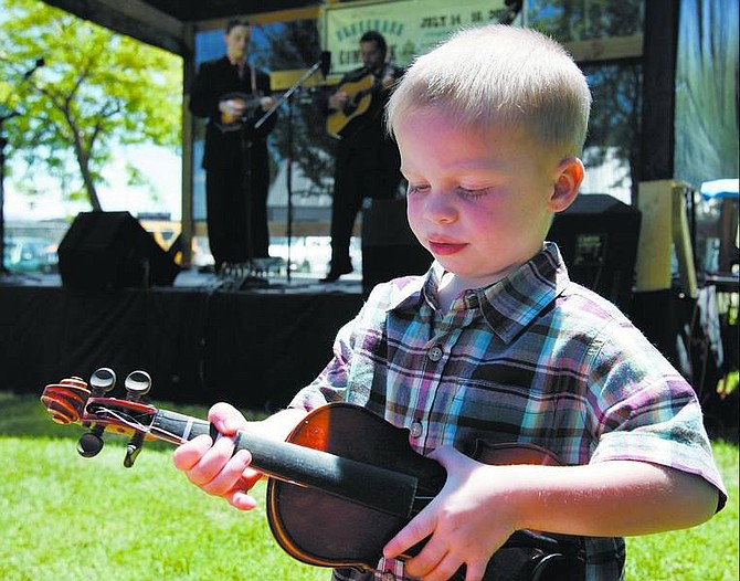 Chad Lundquist/Nevada Appeal Three-year-old Grady Bowen plays along with Digger Davis on Sunday during the Bluegrass on the Comstock Festival in Virginia City.