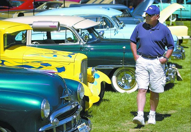 Kevin Clifford/Nevada Appeal Steve Welch of Gardnerville walks by a row of classic cars Saturday afternoon at Mills Park during the Silver Dollar Car Classic.