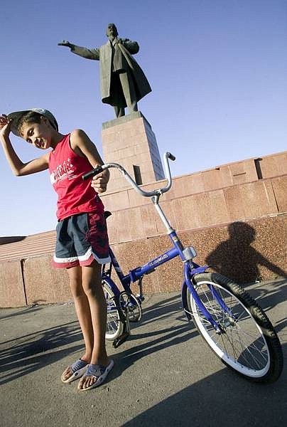 A Kyrgyz boy stands beneath a huge statue of Lenin in the center of Osh.