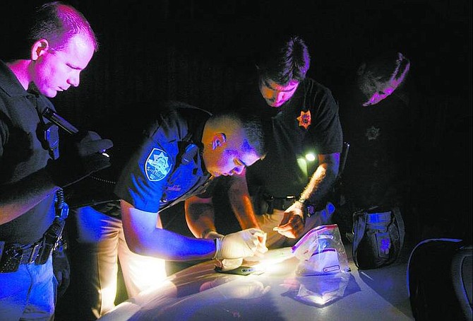 Brad Horn/Nevada Appeal Carson City Sheriff&#039;s deputies and SET team members, from left, Don Gibson, Geoff Rivera, Bill Richards and Sgt. Darrin Sloan work on a drug investigation in Carson City. Rivera is testing a piece of what appears to be methamphetamine. The sample tested positive.