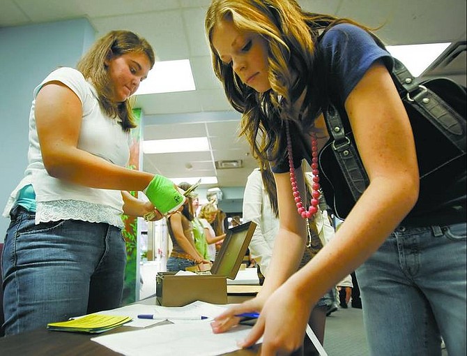 Chad Lundquist/Nevada Appeal Carson High School junior Heidi Flansberg counts money while senior Courtney Hutchins, both National Honor Society officers, signs out tickets Thursday for Friday&#039;s victory dance.