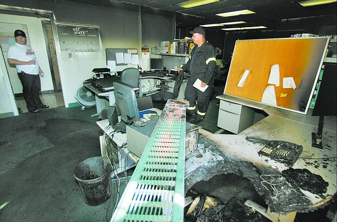 BRAD HORN/Nevada Appeal Carson City fire department investigator Duane Lemons, center, looks through the detectives&#039; unit at the Carson City Sheriff&#039;s office after a fire on Saturday afternoon. The message light on the phone, seen melted in the right lower corner of the photo, was blinking.
