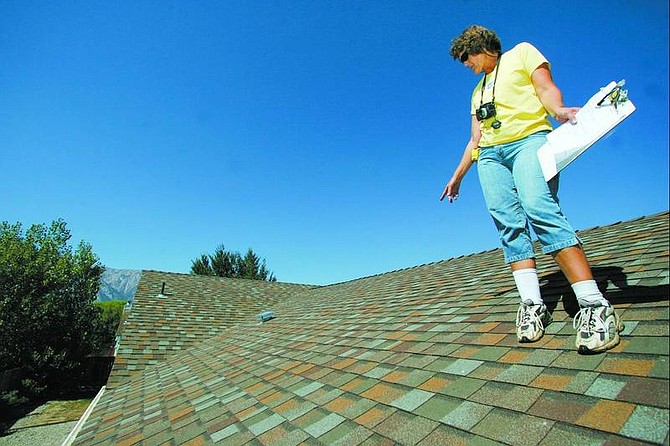 BRAD HORN/Nevada Appeal Karen McGee inspects the roof of a home on Bluerock Road in the Gardnerville Ranchos on Thursday afternoon.