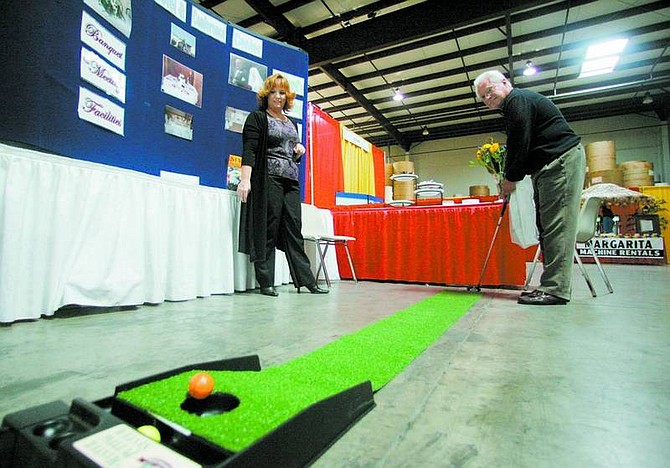 BRAD HORN/Nevada Appeal Chuck Kustler, of Reno, sinks a putt at the Carson City Plaza &amp; Conference Center&#039;s booth at the Business Expo at the Nevada Appeal on Wednesday. Watching is Jennifer Johnson, front desk manager at the Carson City Hotel.