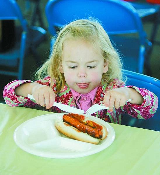 Brad Horn/Nevada Appeal Emma Young, 2, of Carson City, attempts to cut her hot dog during the Carson City Library Foundation&#039;s Oktoberfest 2006 celebration at the Pony Express Pavilion at Mills Park on Saturday.