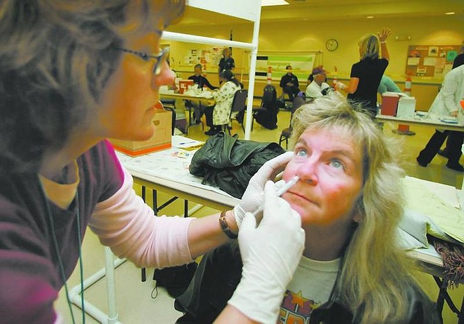 BRAD HORN/Nevada Appeal Maureen Kirkman, a registered nurse with the State of Nevada, injects Flu Mist into Melanie Durandette&#039;s nose at the Carson City Senior Center on Saturday. The patient receives a live flu virus during the procedure. The Carson City Raley&#039;s is hosting flu vaccinations today, Saturday and on Oct. 25-28. The city also offers vaccinations at its Community Health Care Clinic.