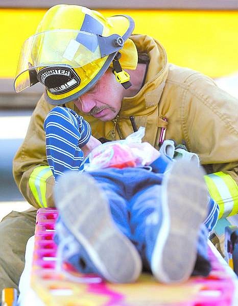 Shannon Litz/Nevada Appeal News Service Firefighter Jeff May asks a student from the school bus where he is hurt.