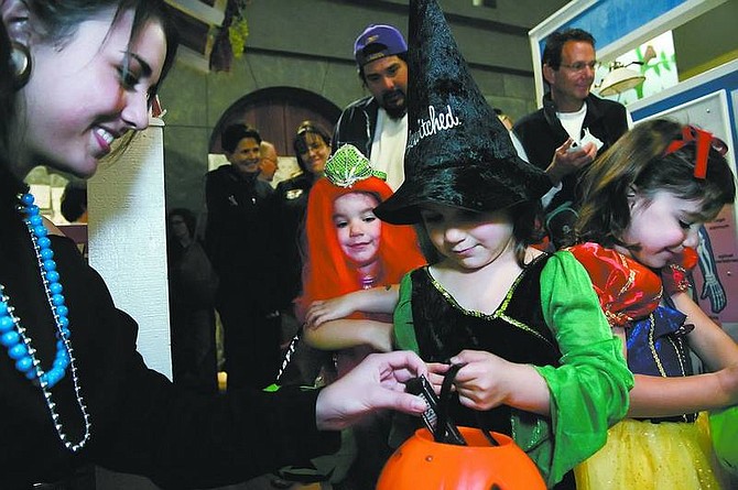 Chad Lundquist/Nevada Appeal File Photo Volunteer Nicole Carlevato, 15, hands out candy to triplets Jane, from left, Susan and Adele Fliegler last year. This year, princesses and pirates are the most-anticipated costumes.