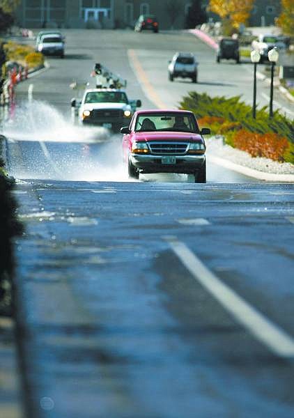 Cathleen Allison/Nevada Appeal Traffic moves through water running down College Parkway on Thursday afternoon as city officials empty the temporary retention basin at the end of Vicee Canyon.