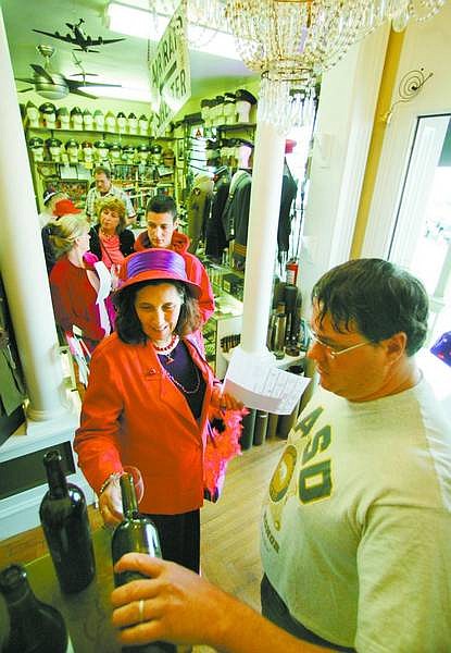 BRAD HORN/Nevada Appeal Gary Cain, owner of Westwall Militaria, pours Terry August, of the Silver State Ladies Red Hat Society, a glass of wine at his store during the inaugural Wine Walk on Saturday.