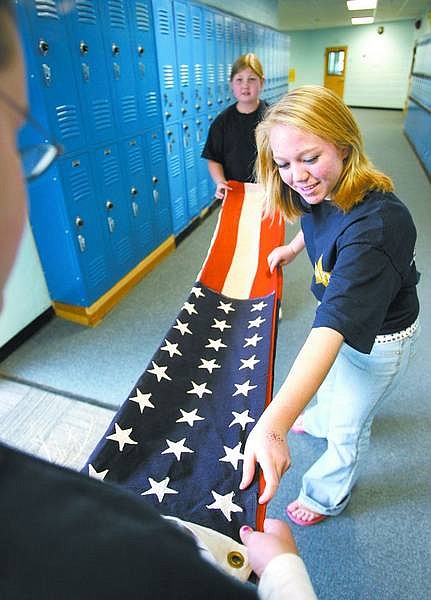 Cathleen Allison/Nevada Appeal file photo Carson Middle School eighth-graders, clockwise from front, Robyn Gowan, Alyssa Brown and Shayna Ruybalidi, all 13, practice folding an American flag in preparation for last year&#039;s Veterans Day Commemoration program honoring former area military personnel.