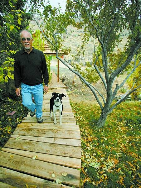 BRAD HORN/Nevada Appeal Silver City resident Bob Elston walks with his dog Phil in their backyard on Friday.