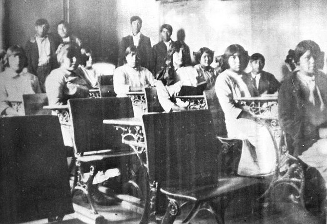 Nevada Appeal file/Stewart Museum photo Stewart Indian School students wearing identical school-issued gowns and suits and required haircuts sit in a classroom.