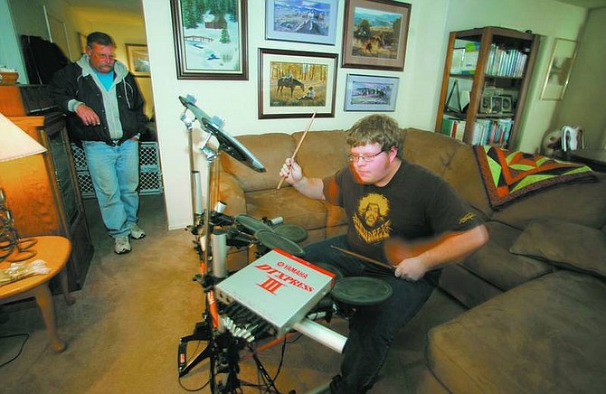 BRAD HORN/Nevada Appeal Lance Cowperthwaite Jr. practices drums in his Carson City living room while his father Lance watches on Sunday afternoon.