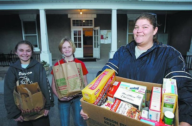 Chad Lundquist/Nevada Appeal Lavurne Jeffreys, right, volunteer Connections coordinator, holds donated food in front of the Dayton Valley Community Center with youth volunteers Cora Jeffreys, 12, left, and Mckensie Greenwalt, 12, on Monday afternoon.
