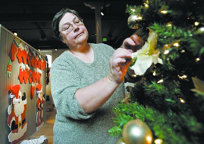 Chad Lundquist/Nevada Appeal Phyllis Sargent, assistant administrator of Library Services for the Nevada State Library and Archives, adds the finishing touches to one of the trees included in the Festival of Trees fundraiser, which runs through Dec. 8.