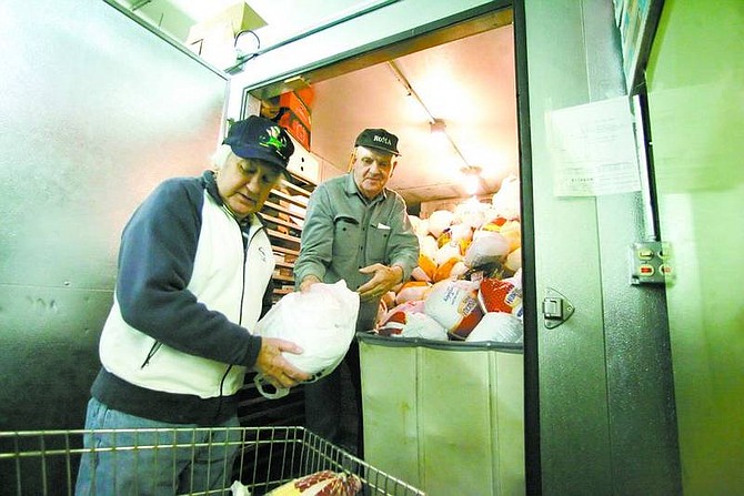 BRAD HORN/Nevada Appeal FISH food manager Jim McMullen, left, and volunteer Don Shearer unload turkeys from a walk-in freezer at FISH on Wednesday morning.