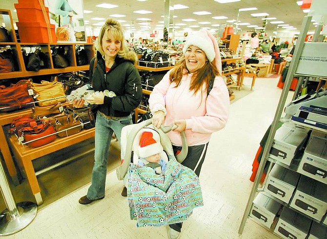 BRAD HORN/Nevada Appeal Lanaia Lammay, left, and Kristina Cormier, shop with Arrigo Cormier, 8-weeks-old, at Gottschalks early Friday morning. The sister-in-laws, who made this a tradition five years ago, shop for about 62 family and friends.