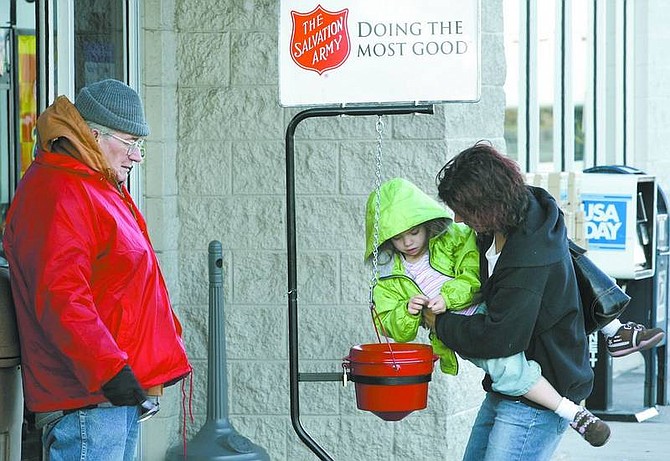 Cathleen Allison/Nevada Appeal Jannell Evans helps her daughter Madison, 4, donate to the Salvation Army on Tuesday afternoon. Red Kettle volunteer Richard Wolfcale, left, braved the cold to ring the bell at the Douglas County Wal-Mart. Salvation Army officials need more volunteers to staff the 19 area locations.