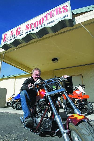 Ernie Magee, owner of E&amp;G Scooters, sits on a  miniature chopper in front of his store at 2020 Highway  50 E., on Wednesday.    Chad Lundquist/ Nevada Appeal