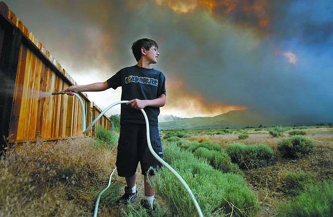 Chad Lundquist/Nevada Appeal File photo Matthew Roberts tries to keep his backyard fence wet at the end of Red Rock Road during the Linehan fire in July, but his attention is momentarily diverted as flames from the fire threaten. The Linehan Complex fire threatened 200 homes.