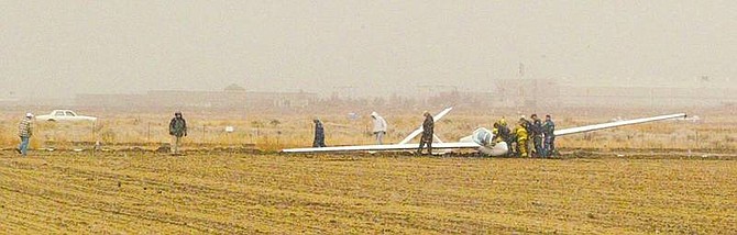 SARAH KING/Nevada Appeal News Service Rescue workers attempt to clear the scene after a glider crashed in a field near Minden Airport on Wednesday. The pilot and passenger-co-pilot were both taken to the hospital with minor injuries.