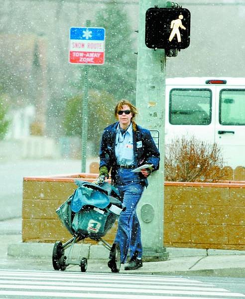 Laurinda Reynolds, a letter carrier with the Carson City Post Office, crosses Carson Street during a snowstorm Wednesday. Three to six inches of snow is expected in the Sierra Nevada above 7,000 feet.  Brad Horn/ Nevada Appeal
