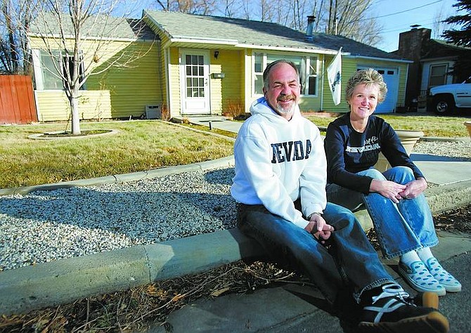 Chad Lundquist/Nevada Appeal Jeff and Ann Erwin sit on the curb in front of their home near Telegraph and Iris streets on Saturday. Last year at this time, the couple woke up to a flooded garage and knee-deep water in their front yard.
