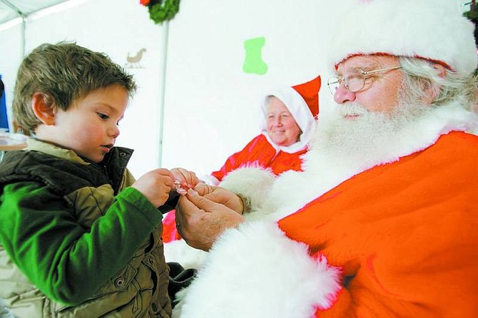 BRAD HORN/Nevada Appeal Santa Claus helps Seth Rotoli, 3, open his candycane at the Christmas at the Park celebration at Washoe Lake State Park on Saturday.
