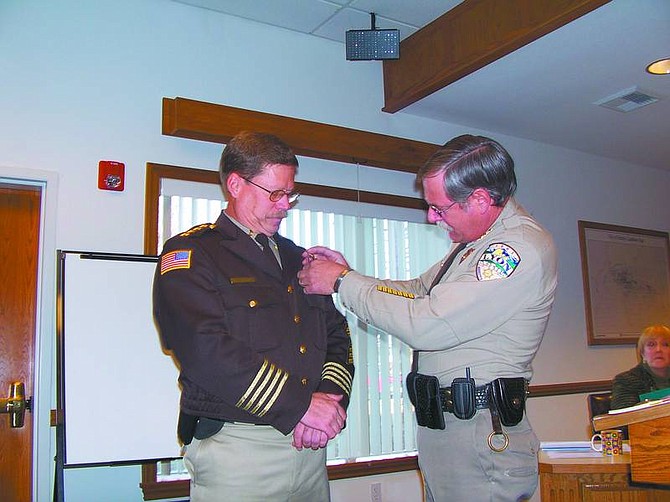 Karen Woodmansee/Nevada AppealOutgoing Lyon County Sheriff Sid Smith pins a badge on incoming Sheriff Allen Veil at the Lyon County Commission meeting Tuesday.