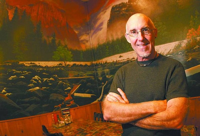 Trevor Clark/Nevada AppealRobert Bucknell poses in front of a mural of El Capitan in Yosemite National Park on July 15. Bucknell, who paints murals for companies like Cabela&#039;s, painted the mural in Mom &amp; Pop&#039;s Diner on Carson Street about 10 years ago.