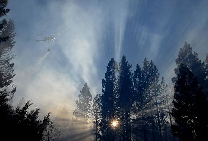 Kevin Clifford/Nevada AppealA helicopter drops water onto hots pots as it flies through smoke caused by the Washoe fire near Tahoe City on Saturday.