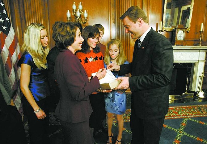 Cathleen Allison/Nevada Appeal Congressman Dean Heller, right, asks Speaker of the House, Nancy Pelosi, D-Calif., to sign the family Bible on Thursday night after using it during his mock swearing-in. Families were allowed to take photographs with Pelosi at the U.S. Capitol following the official ceremony that was conducted en masse for the 435 house members. From left, Hilary Heller, 21, Pelosi, wife Lynne Heller, Drew, 16, Emmy, 11, and Dean. The Bible was a gift to Lynne and Dean from the church where they married in 1984.
