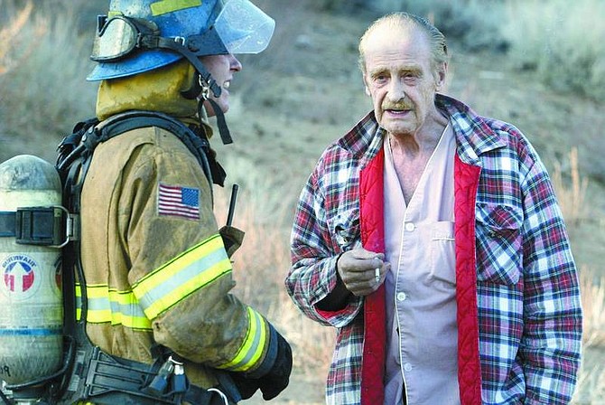 Cathleen Allison/Nevada Appeal Home owner David Eddings talks with a Carson City firefighter Thursday afternoon outside his North Carson City home. Eddings accidentally destroyed his office by igniting gasoline while working on his vehicle.