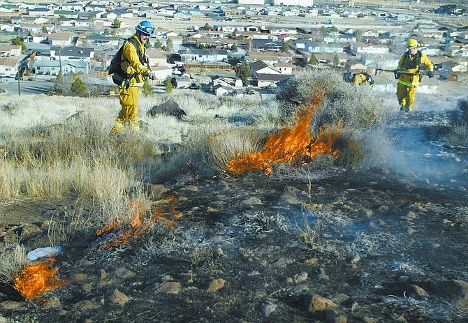 Carson City firefighters extinguish hot spots Friday afternoon at a 37-acre brush fire near Flowery Avenue in Dayton. From left, paramedic Jim White, Capt. John Easterling and firefighter Travis Howe were among the more than 65 area firefighters who responded from eight agencies.  Cathleen Allison/ Nevada Appeal