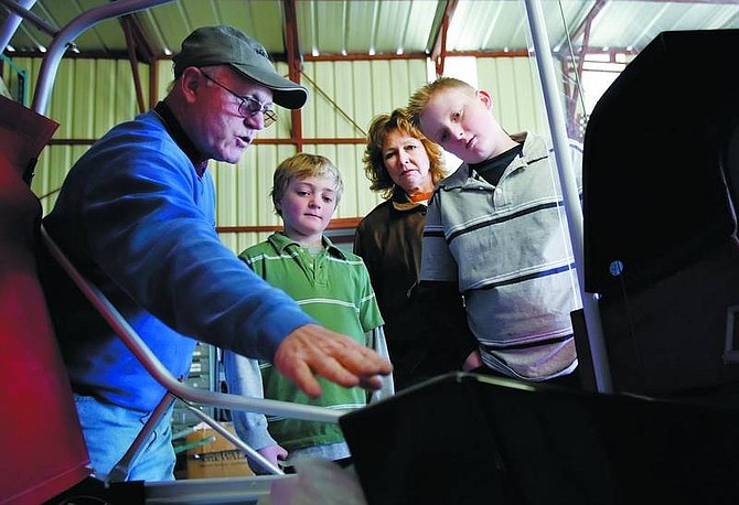 Chad Lundquist/Nevada Appeal  Mike Reynolds, left, and Merry Romine, center, show Caulin Schadeck, 9, and his brother Caleb, 11, the construction progress on Reynolds H-Air light sport airplane as part of the young eagles program.