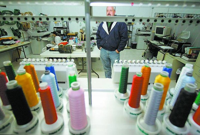 BRAD HORN/Nevada Appeal Curtis Siever, owner of Visual Identity Products in Carson City, is framed by an industrial embroidery machine at the business on Wednesday.
