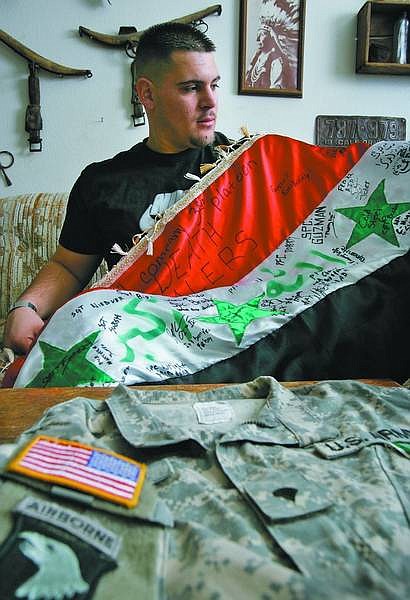 Chad lundquist/Nevada Appeal  Travis Fratis, 21, holds at his home Tuesday an Iraqi flag signed by fellow platoon members while on duty for the U.S. Army in Iraq.