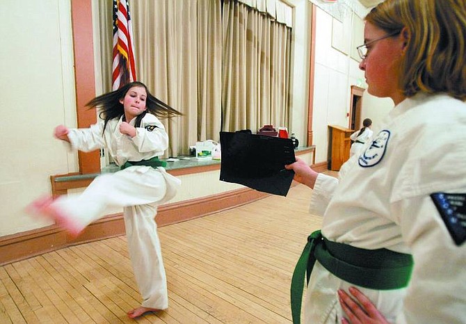 Chad Lundquist/Nevada Appeal Amber Gaab, 12, left, practices kicking a target held by Kalee Alexander, 10, during a karate class at the Dayton Community Center.