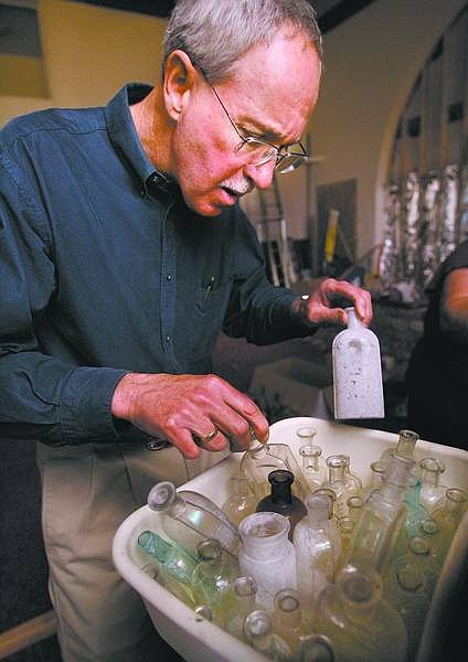 Cathleen Allison/Nevada Appeal  Rev. Bruce Kochsmeier of First Presbyterian Church looks through some of the hundreds of bottles unearthed during excavating work being done at the church recently.