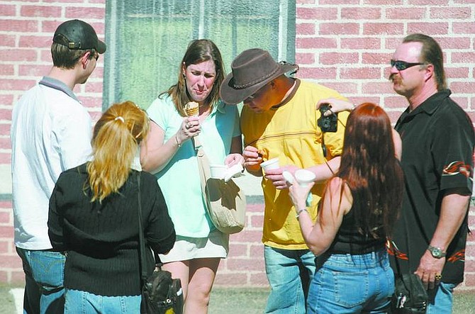 Photos by BRAD HOrn/Nevada Appeal ABOVE:Emily Schoen reacts to eating a mountain oyster while her husband, Scott, in cowboy hat, watches, and friends take pictures at the Mountain Oyster Fry in Virginia City on Saturday. The group, all from Madison, Wisc., are staying in Reno for a convention. Scott Schoen said that once he heard about the event featuring concoctions from sheep testicles he made plans to attend the unusual gathering for the first time. His wife washed the taste down with ice cream. BELOW: John Wood, center, fries mountain oysters while customers wait.