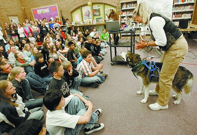 Chad Lundquist/Nevada Appeal Lorraine Temple of Homer, Alaska, and her husky, Buckeye, demonstrate how a sled dog harness works during a presentation at Eagle Valley Middle School on Tuesday.