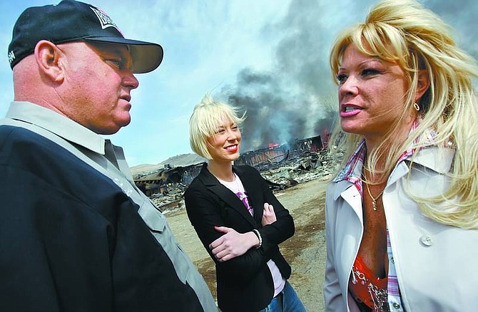 Chad Lundquist/Nevada Appeal Moonlite BunnyRanch brothel owner Dennis Hof talks with two of his working girls Brooke Taylor, center, and a woman who identified herself as &quot;Air Force Amy,&quot; right, as the remains of the former Mustang Ranch 2 brothel burns during a training exercise on Sunday.