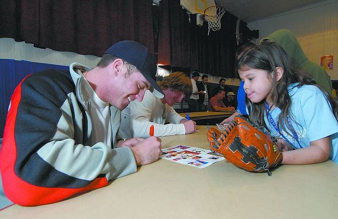 Published Caption: Published Caption: Kevin Clifford/Nevada Appeal Ryan Sanchez, 7, right, watches as Darrell Rasner signs an autograph for her Friday afternoon at the Boys and Girls Club in Carson City.  Darrell and Jake Rasner, natives of Carson City, are two of several professional baseball players that are holding a clinic to raise funds for a new baseball field for the Boys and Girls Club.