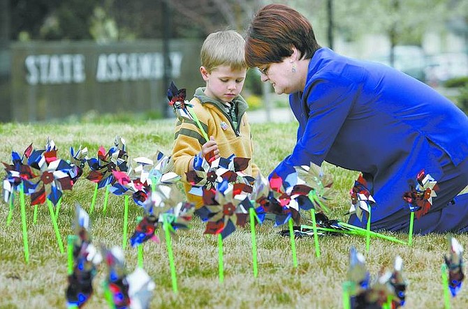 Cathleen Allison/Nevada Appeal Mary Liveratti, with Carson City Health and Human Services, helps Kellen George, 5, place pinwheels on the Legislative lawn Thursday morning. Child advocates planted the pinwheels in recognition of Child Abuse Prevention Month, placing 422 pinwheels, one for each case of child abuse that was reported in Carson City in 2006.
