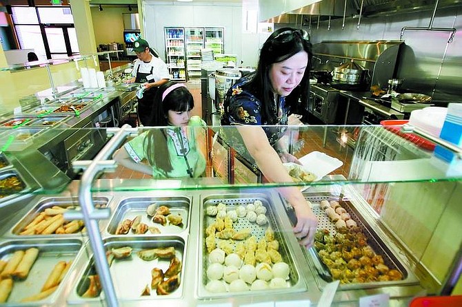 BRAD HORN/Nevada Appeal CaiE George prepares some lunch samples for City Hall while her daughter Ashley, 7, waits to assist her mother with the delivery on Friday at CaiE&#039;s Oriental Caf&#233;. The cafe opened Friday on the northeast corner of Proctor and Carson streets.