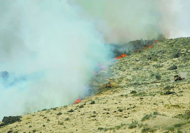 BRAD HORN/Nevada Appeal Bulldozers build a fire line at the top of a hill in Pleasant Valley to help combat a brush fire that burned about 75 acres Friday morning. Officials said they hoped to have the fire contained by the end of the day.