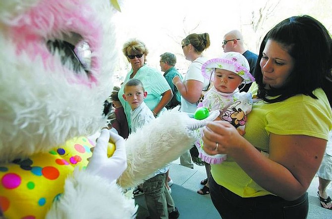 Eight-month-old Stacy Croteau, center, with help from mom Mandy, is handed her first Easter egg by the Easter Bunny on Sunday. More than 3,000 children celebrated Easter at the Governor&#039;s Mansion.  Chad Lundquist/ Nevada Appeal